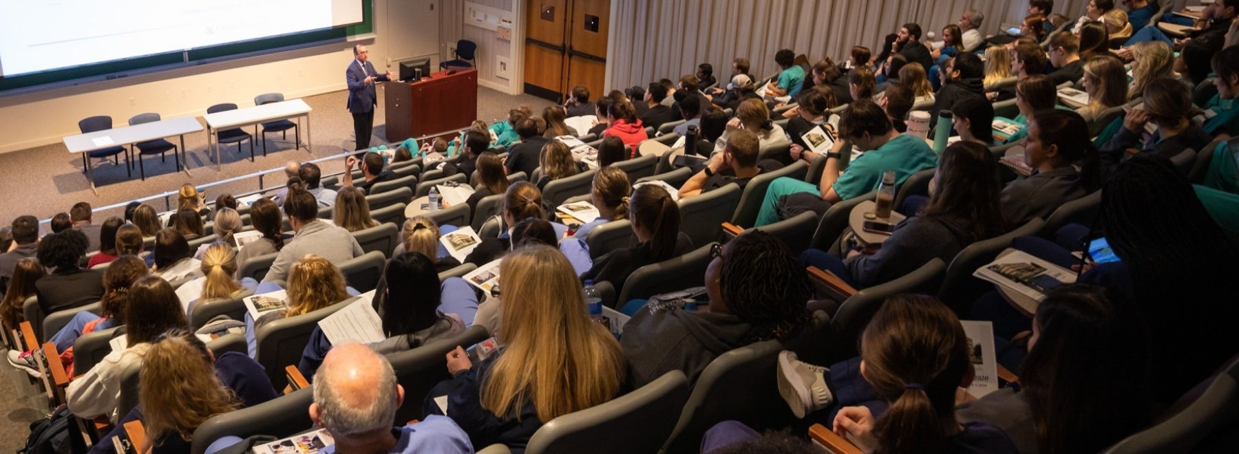 Participants listen to a lecturer during grand rounds.